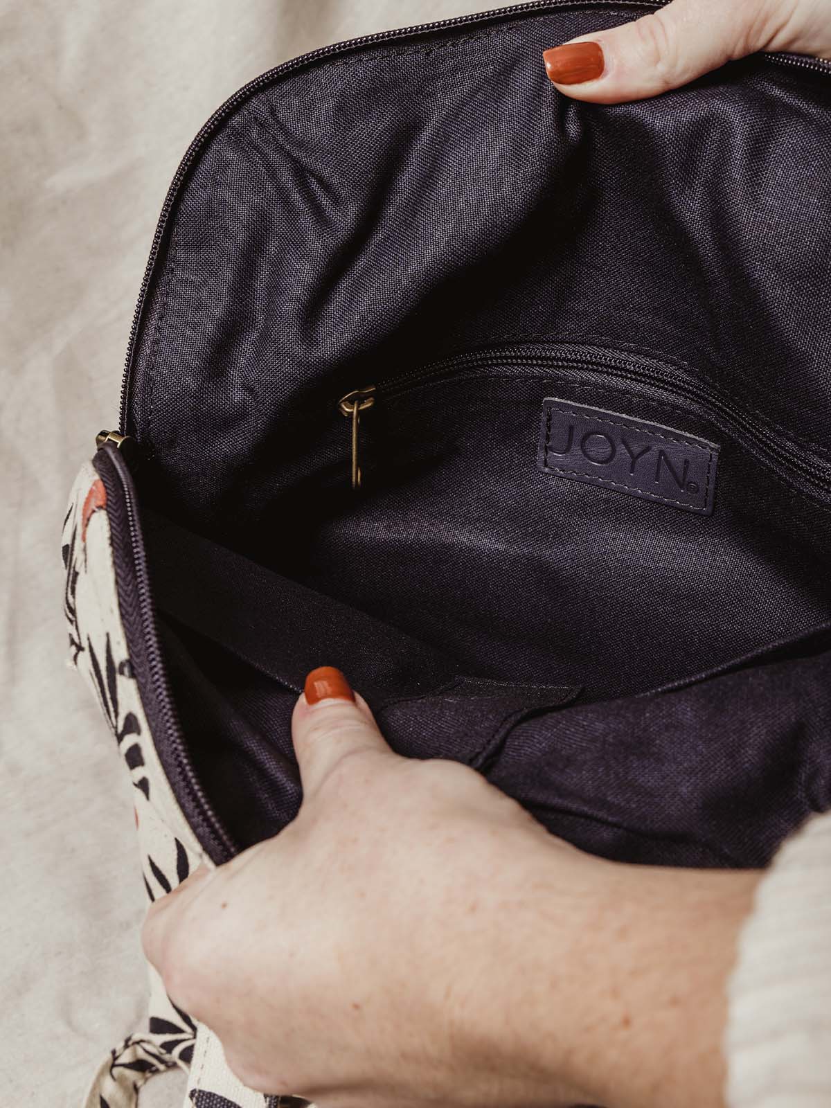 Model opening bag to show interior zipper for additional storage.