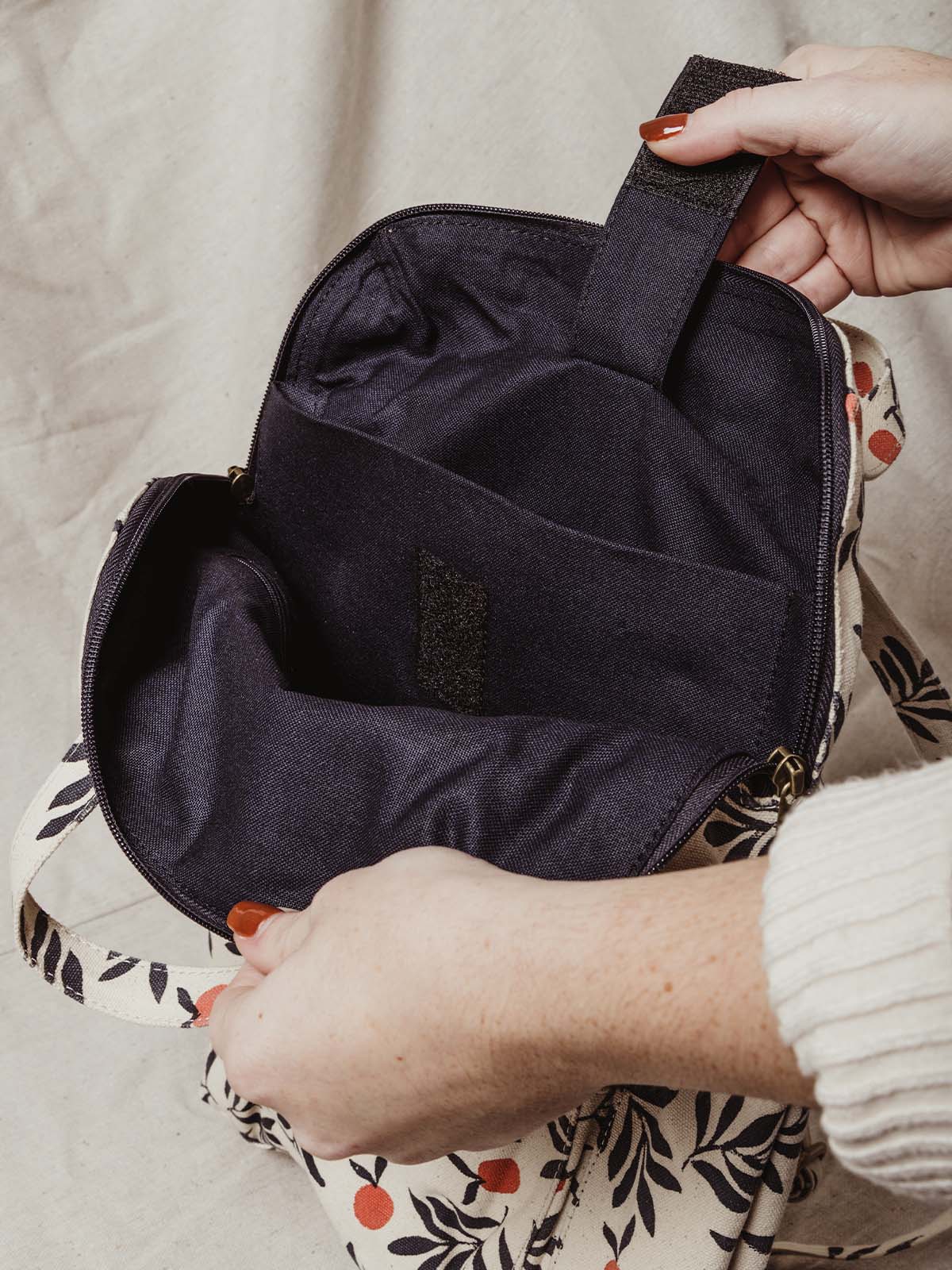 Model opening bag to show inside of the bag. Two pockets - one for a laptop and the other for addition storage.