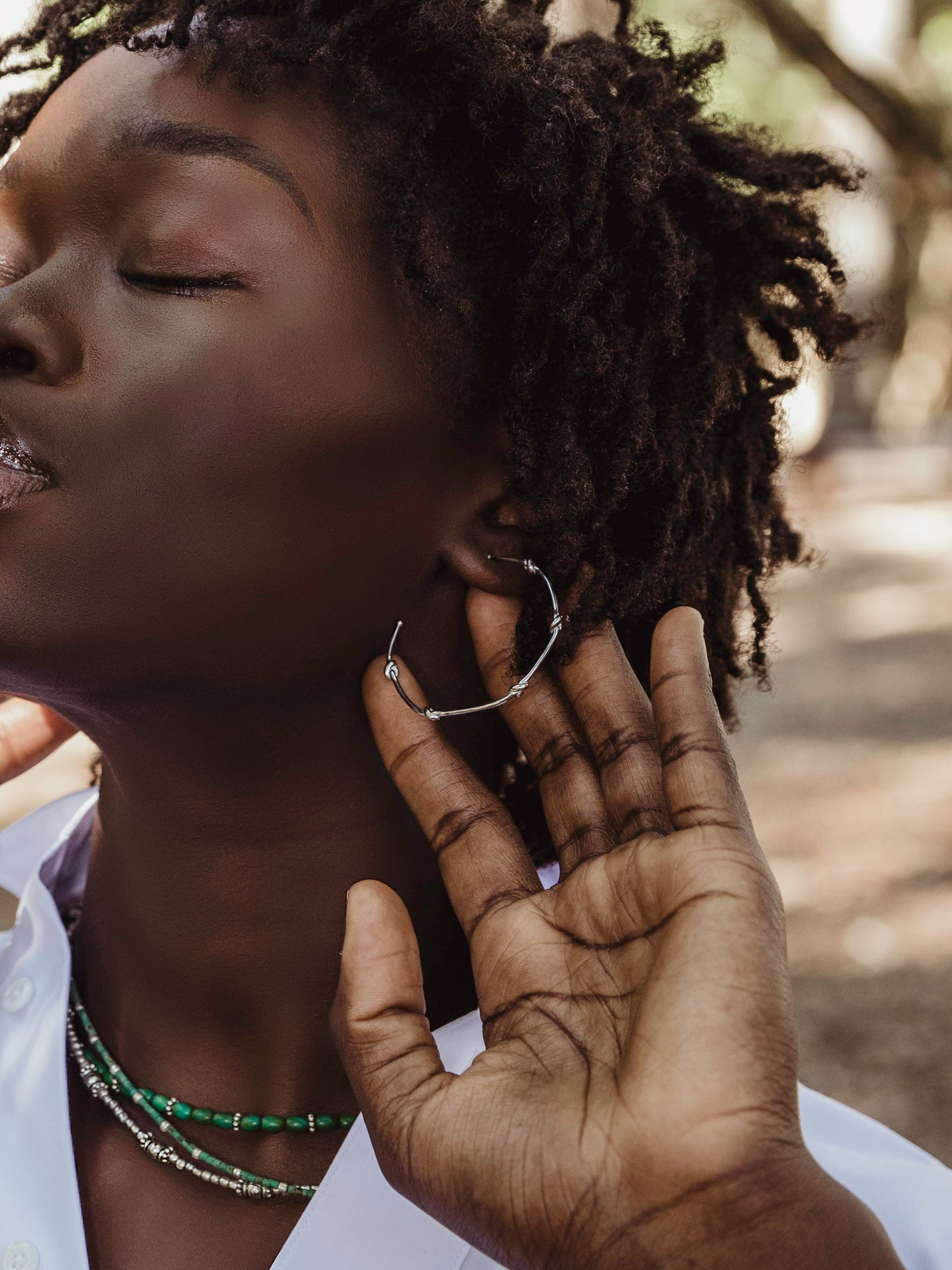 Female model wearing classic hoop design with 5 knots in the hoop's metal.