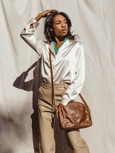 Female model holding half-moon leather hand back cross body