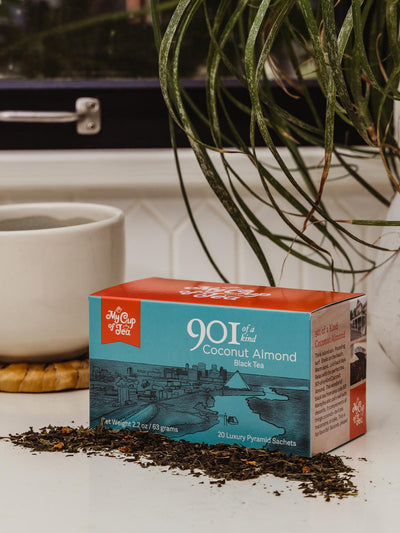 Coconut Almond Tea box on counter with coffee cup and greenery.