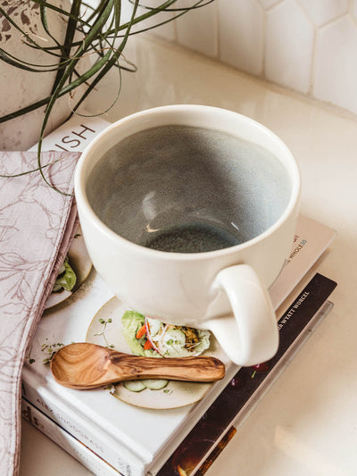 Ceramic white mug onto of books on counter with blue glaze inside mug.