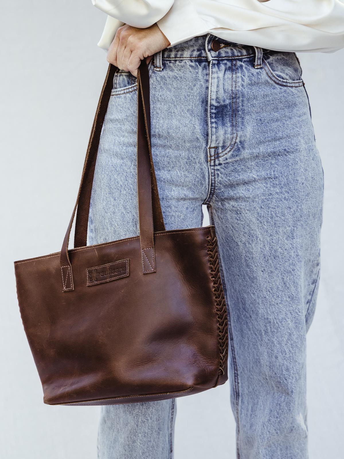 Female holding dark brown braided purse.