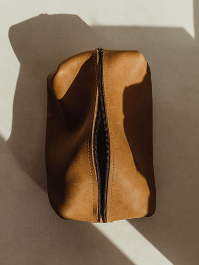 Carmel colored leather bag with zipper on white table.