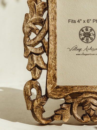 Wooden picture frame with carved details on a white table. 