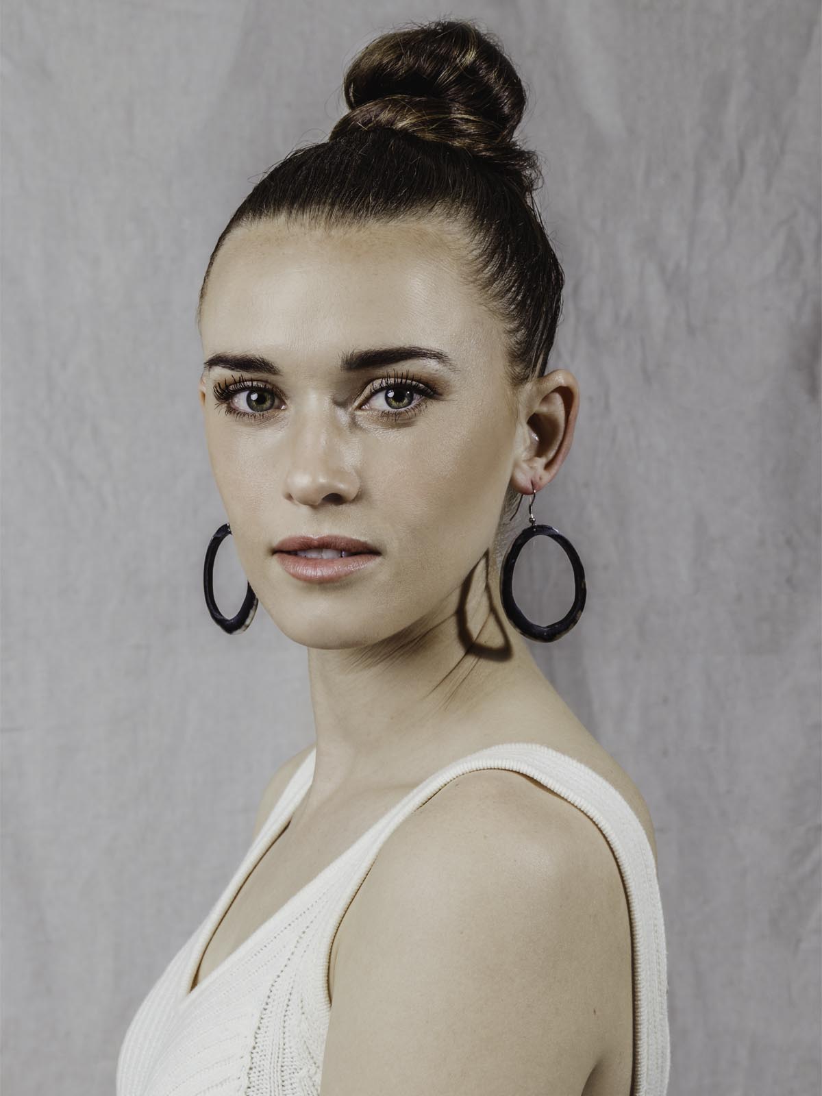 Model wearing horn Hoop Earrings. Large hoop shape with  black, brown, and white color tones