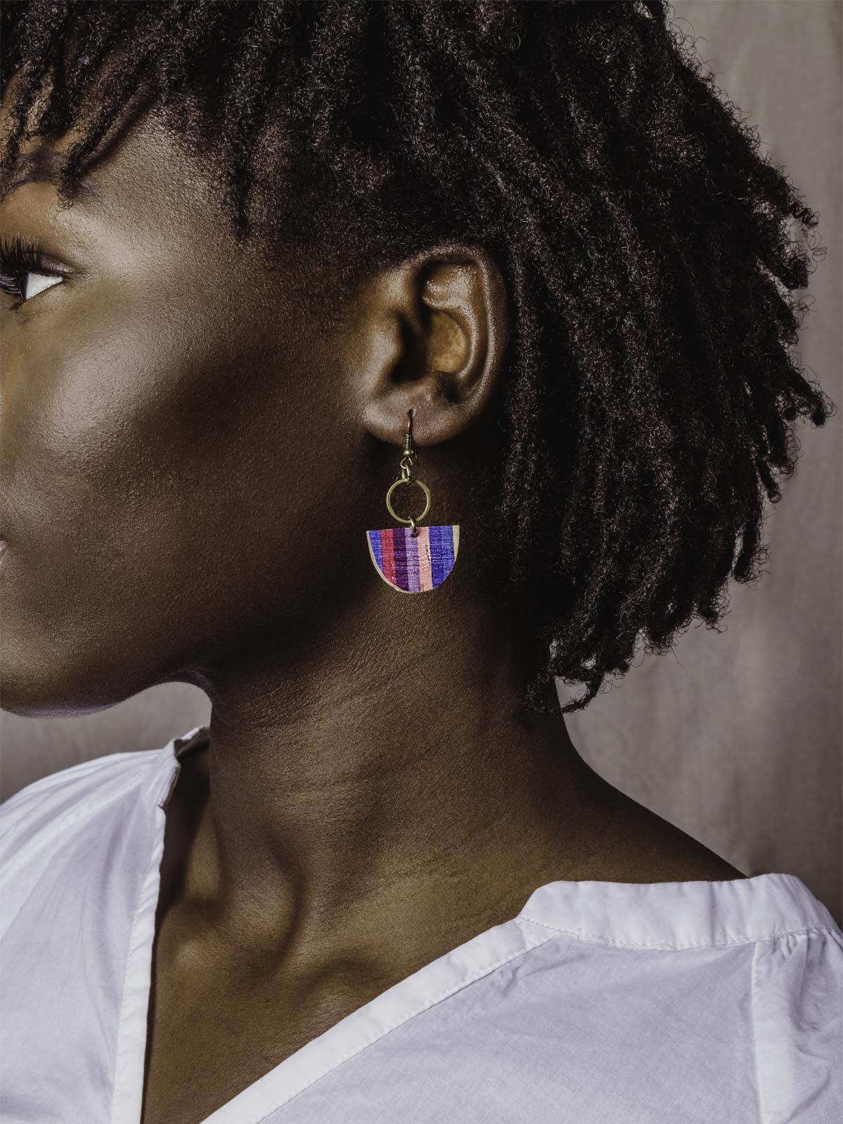 blue, pink, maroon, purple, blue and yellow half circle earrings with gold metal on model wearing white shirt.