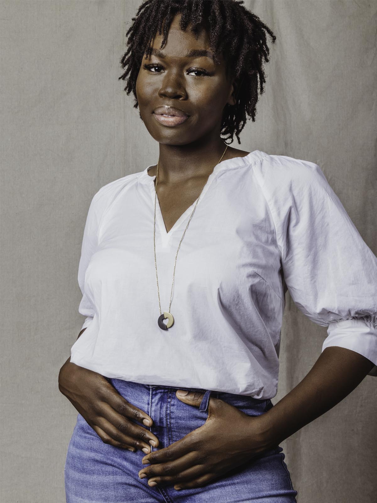 Model wearing white top with jeans and two toned heart necklace. 