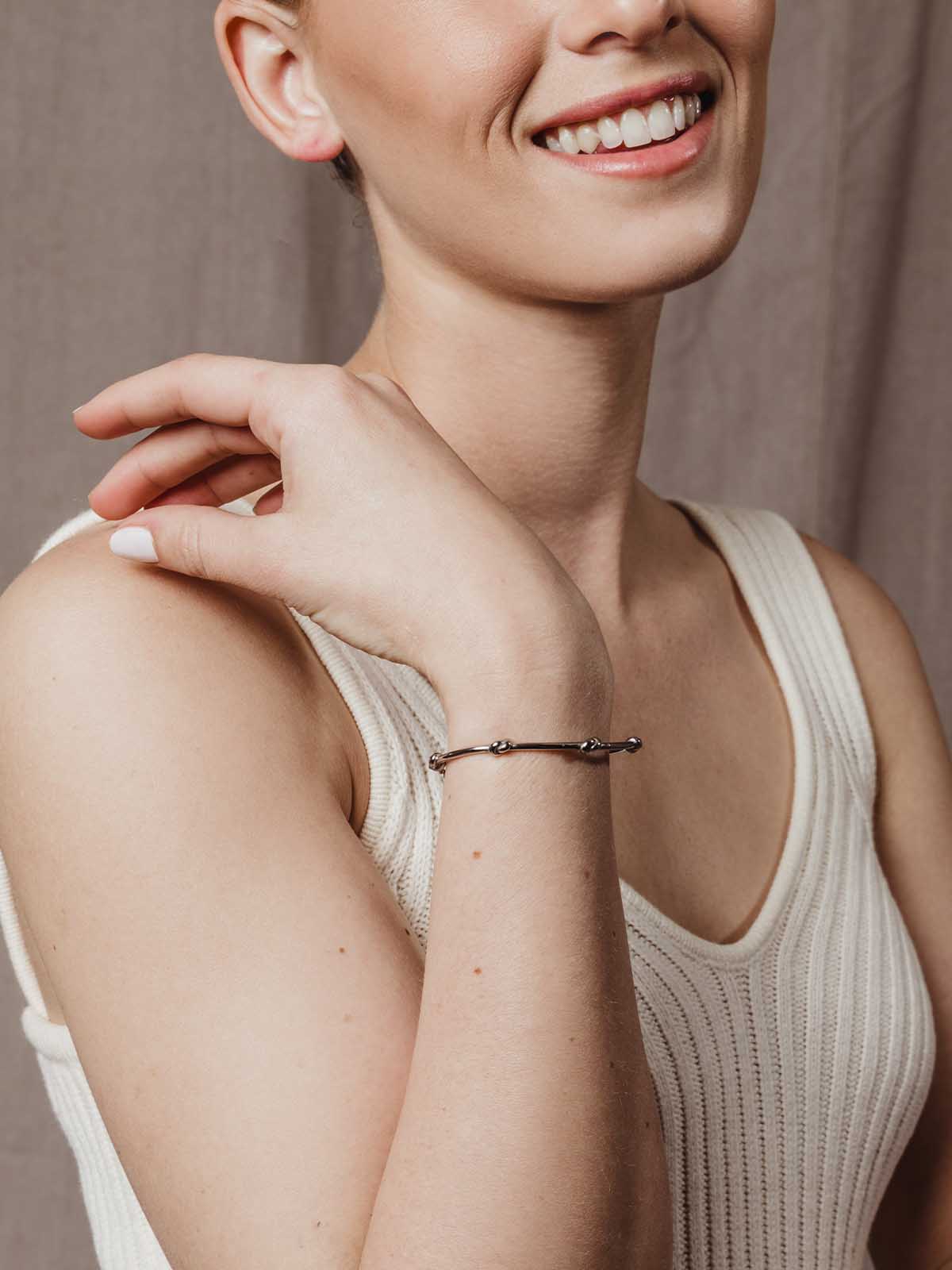 close up of model wearing silver knot bracelet with chain