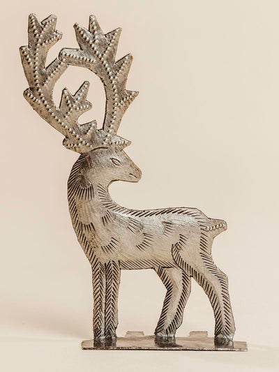 Silver metal reindeer standing on a beige background. 