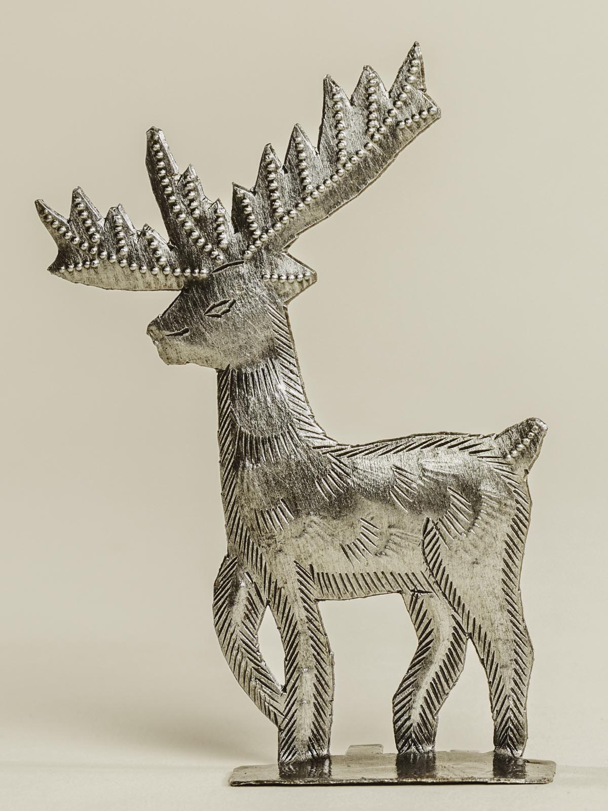 Silver reindeer standing on a beige background. 