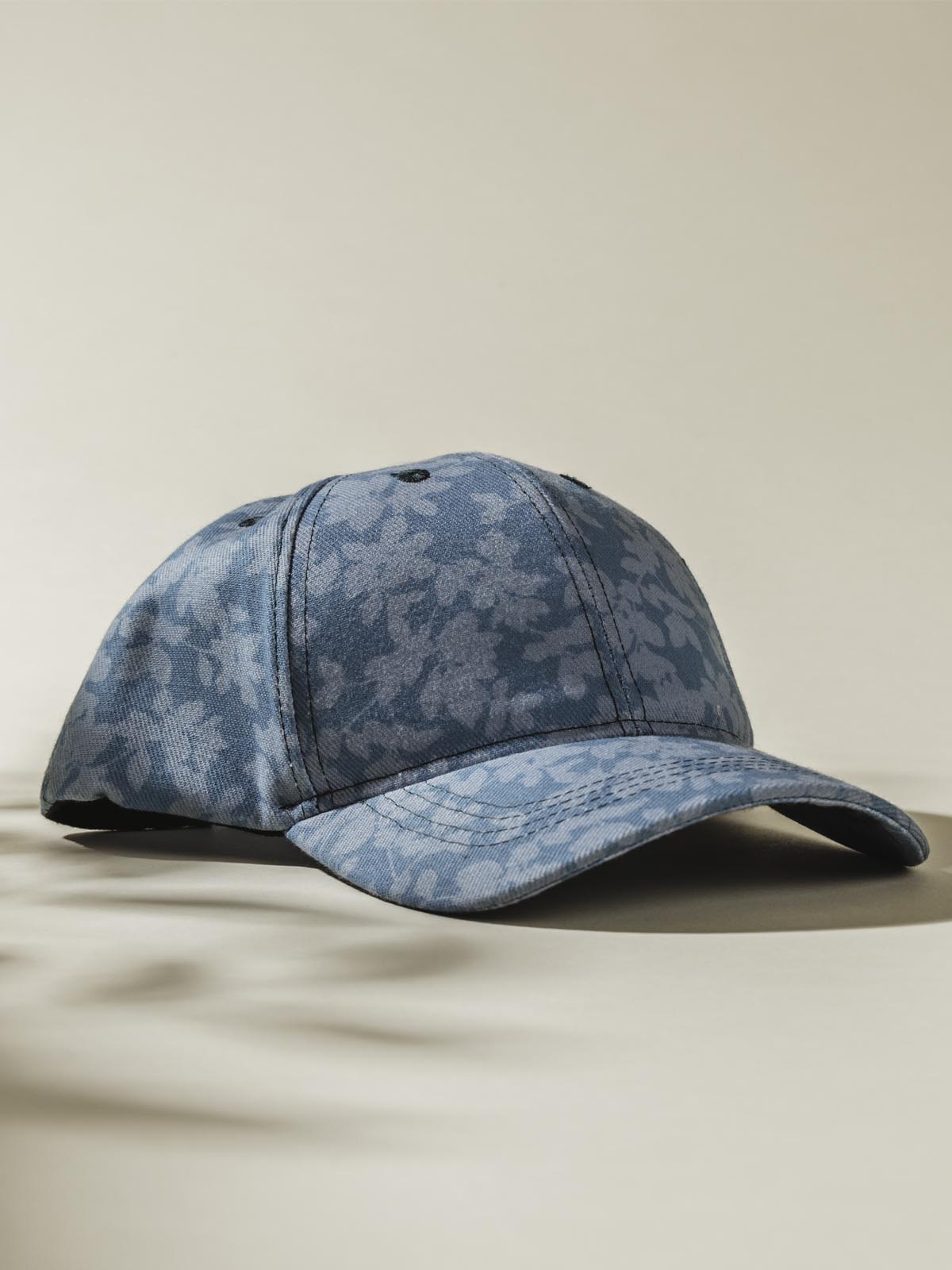 Teal Hat with light floral design on tan background. 