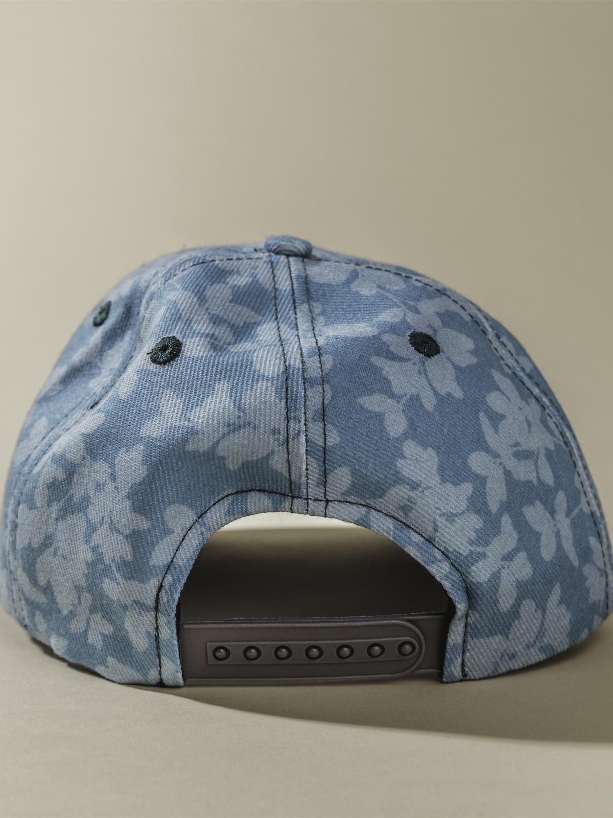 Back of teal Hat with light floral design on tan background.