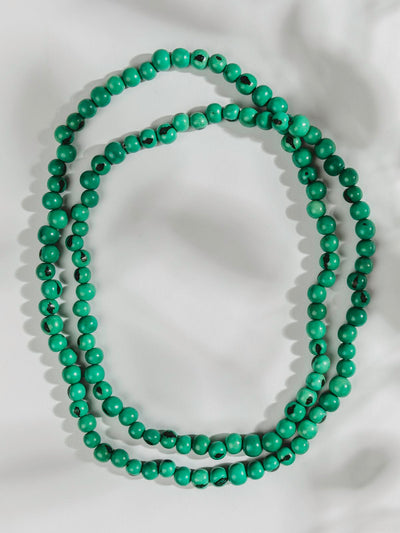 Turquoise necklace laying on a white surface.