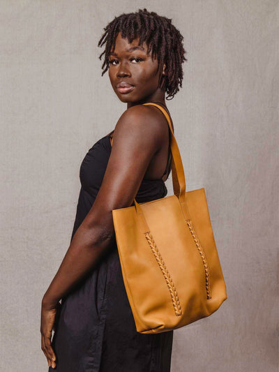 Model with tote back over shoulder in a black dress.