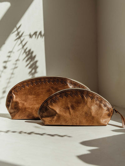 Small and large leather pouch totters on white table 